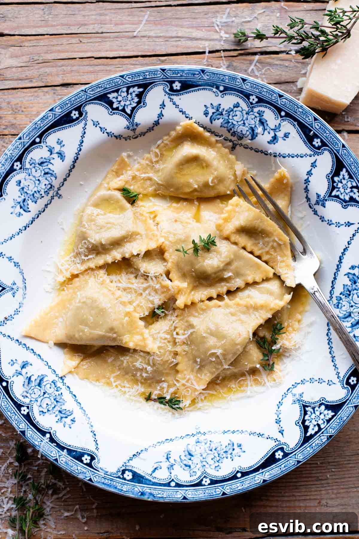 An overhead shot of golden Triangoli pasta filled with mushroom and Taleggio cheese, served in a vibrant blue bowl with a glistening butter sauce, ready to be enjoyed.