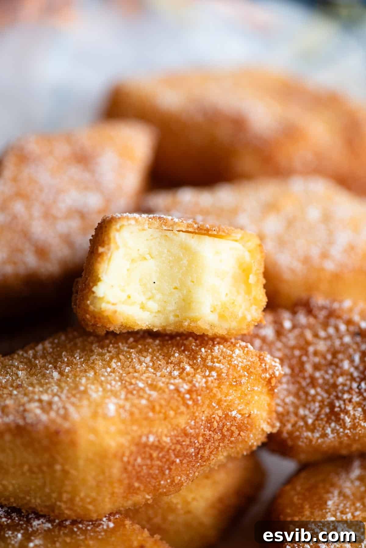 A close-up shot of Crema Fritta (deep-fried custard) cut in half, revealing its creamy, smooth interior and the perfectly crispy, golden-brown crust.