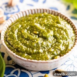 A close up cropped image of vibrant green pistachio pesto in a small dish.