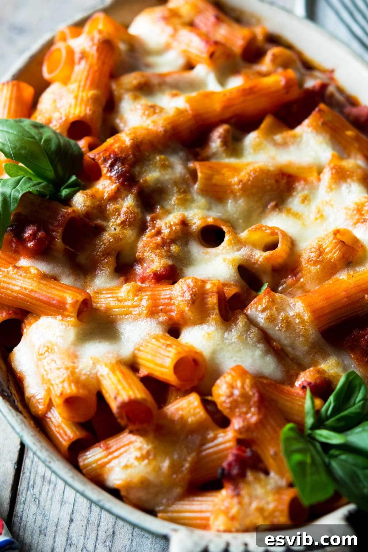 a close up shot of a sausage pasta bake with melted mozzarella in a large dish A close-up shot of cheesy baked pasta, showcasing the melted mozzarella and rich sauce.