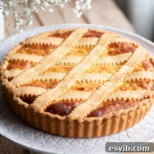 A cropped square image of a delicious Pastiera Napoletana (Italian Easter dessert) on a cake stand, showcasing its golden crust and traditional lattice topping.
