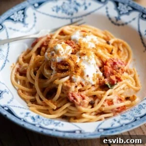 A cropped image of delicious spaghetti in a rich roasted cherry tomato sauce, ready to be served in a blue bowl.