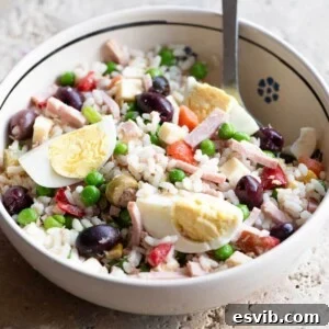 A cropped square image of an Italian rice salad in a bowl topped with eggs.