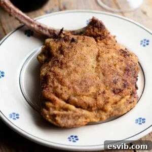 A cropped image of an Italian breaded veal chop on a plate, ready to be enjoyed.