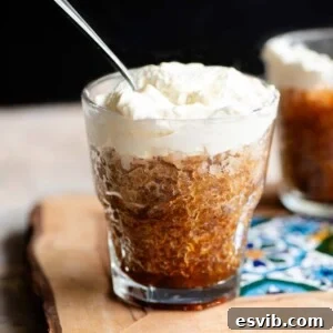 A cropped square image of a small glass filled with coffee granita and topped with whipped cream.