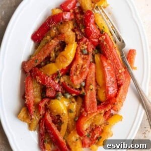 A cropped image of sauteed peppers mixed with capers and breadcrumbs on a white oval serving plate.