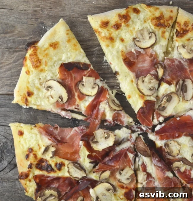 An insanely delicious Cheesy Speck and Mushroom Pizza recipe that is guaranteed to be your new favourite. www.insidetherustickitchen.com A close-up of pizza dough being topped with the creamy Fontal cheese mixture, showcasing the rich texture and even spread before other toppings are added. The focus is on the preparation of the cheesy base.