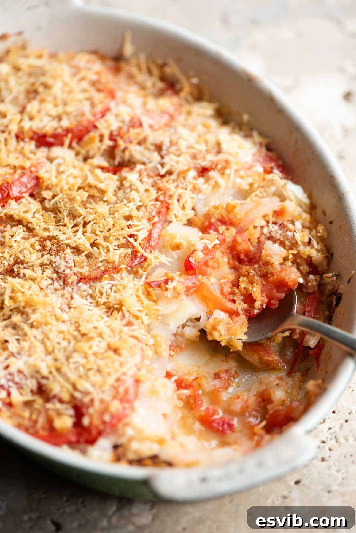 A side shot of Patate alla Lucana in an oval baking dish, showing the layers of potatoes and tomatoes, topped with a golden crust.