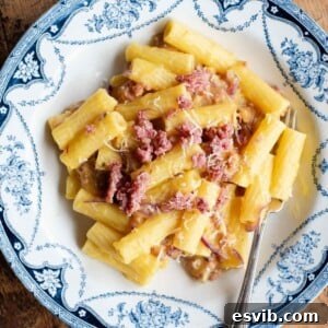 An overhead shot of potato, saffron and sausage pasta in a blue and white bowl.