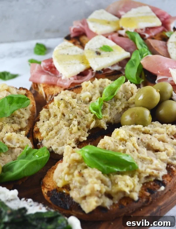 Crostini Three Ways Recipe - Delicious Stracchino and Spinach Crostini! Close-up of a crostini topped with creamy stracchino cheese and wilted spinach, garnished with fresh herbs.