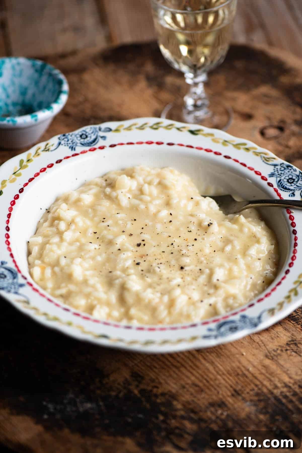 Creamy Fontina Risotto 2 A bowl of cheesy Risotto alla Valdostana sitting on a wooden board, garnished with fresh herbs.