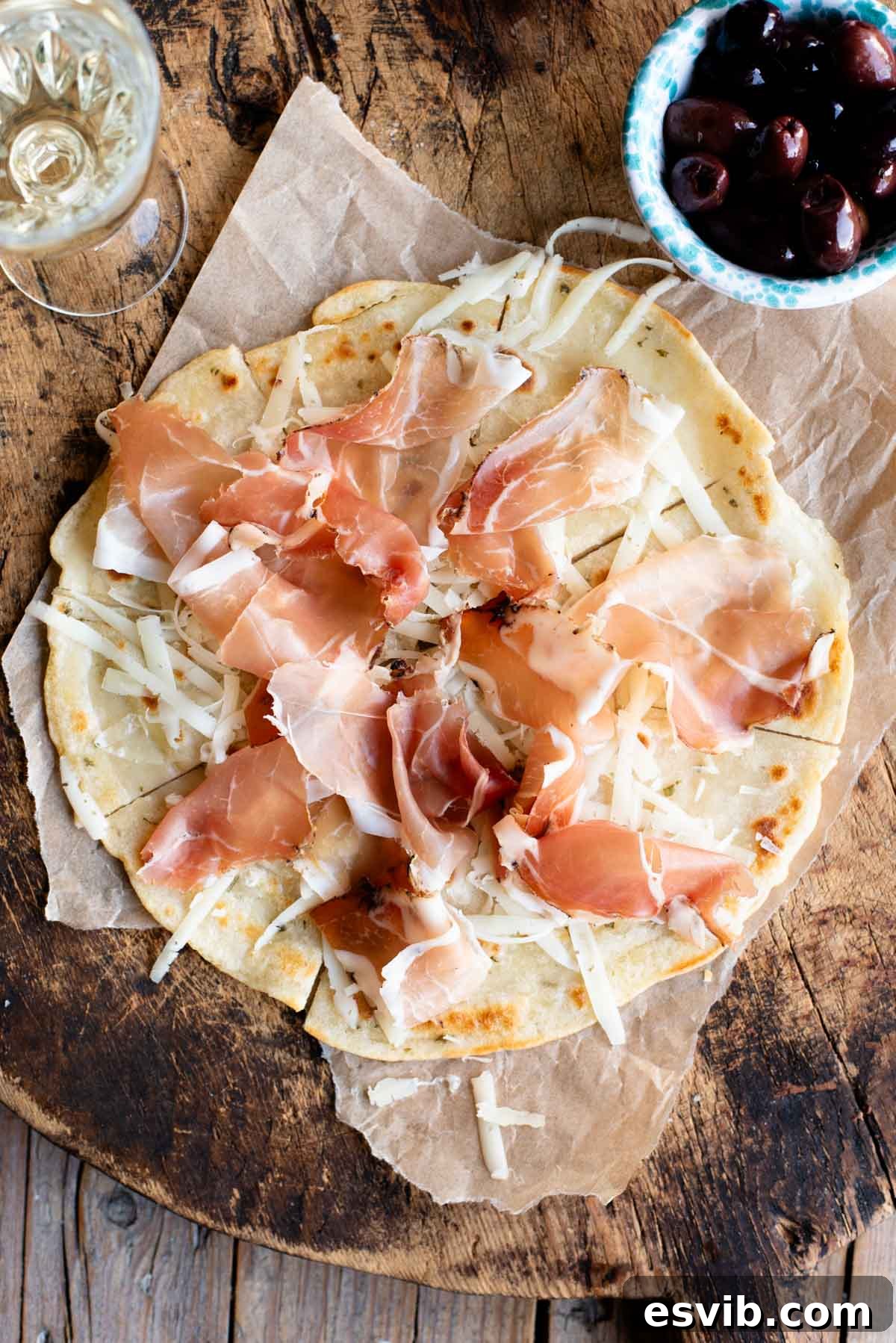 Brustengo: Umbria's Rustic Flatbread 2 An overhead shot of Brustengo, an Italian flatbread topped with cured meat and cheese on a wooden board.