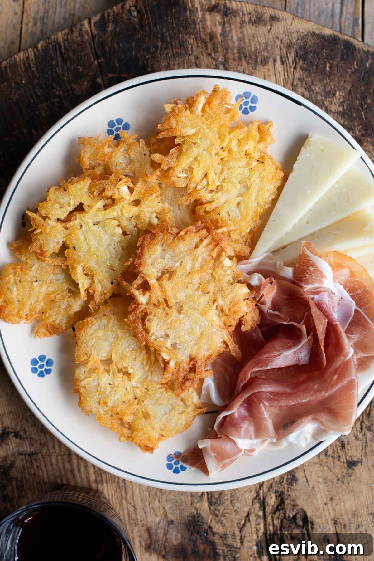 An overhead shot of authentic Tortei di Patate, crispy Italian potato fritters, arranged on a plate with an assortment of cured meats and cheeses, showcasing a delicious Italian snack.