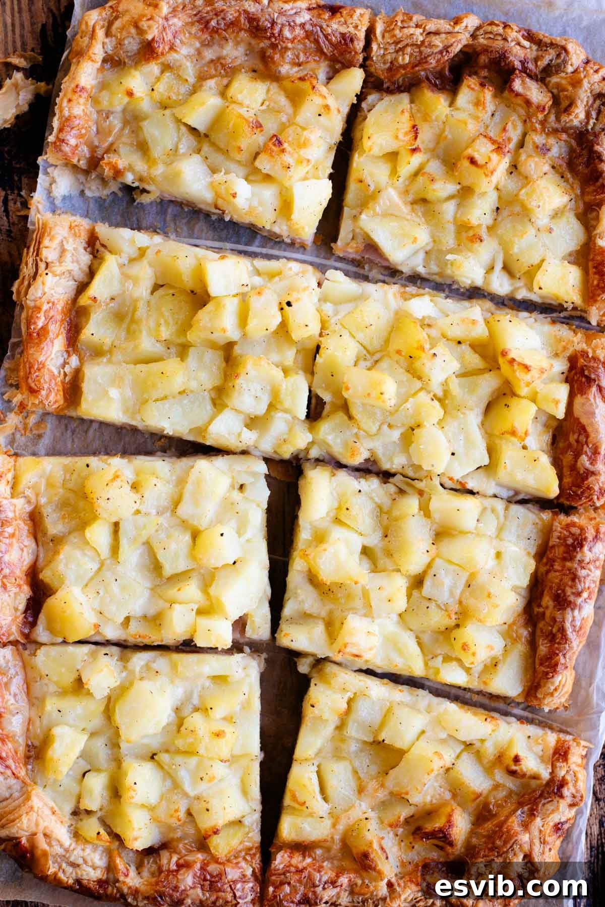Flaky Potato & Cheese Tart 2 An overhead shot of a puff pastry tart topped with potatoes, ham and cheese and cut into 8 slices.