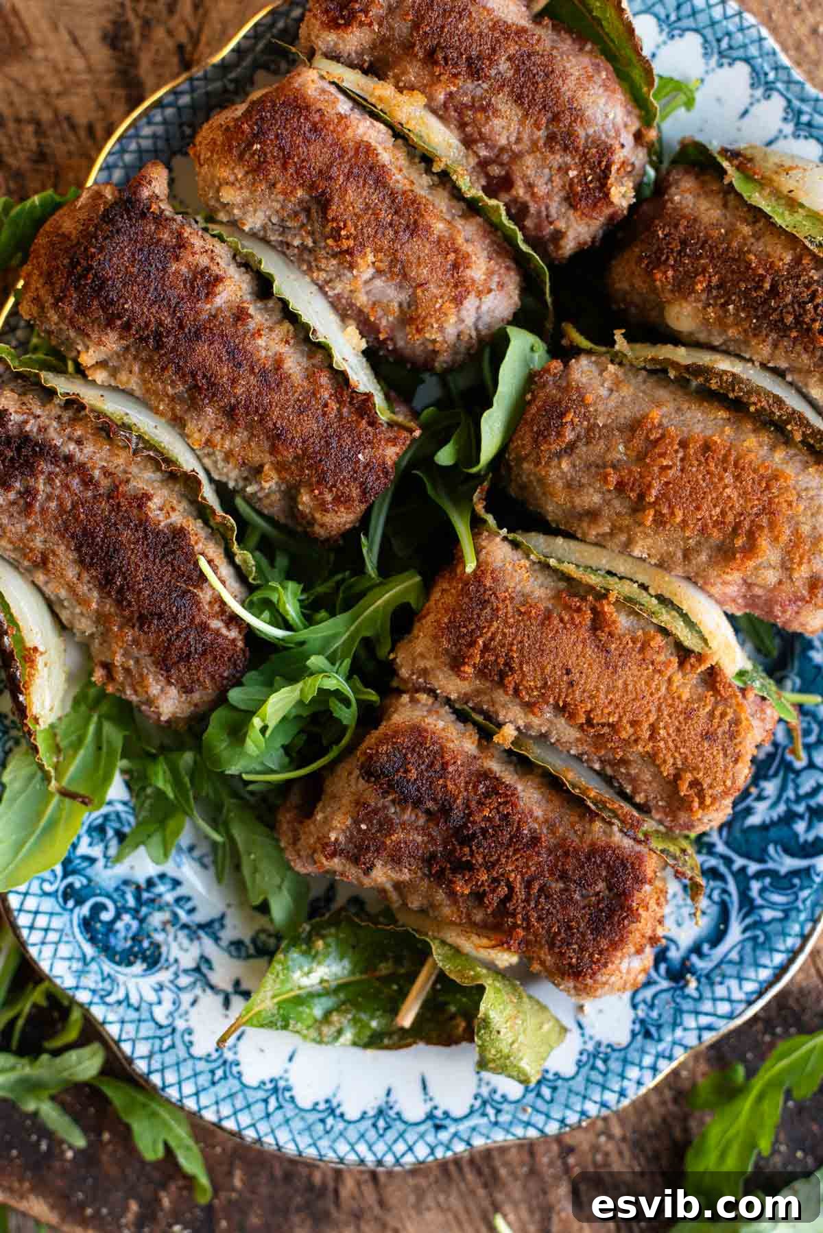 An overhead shot of Sicilian involtini on skewers with breadcrumbs, garnished with fresh herbs.