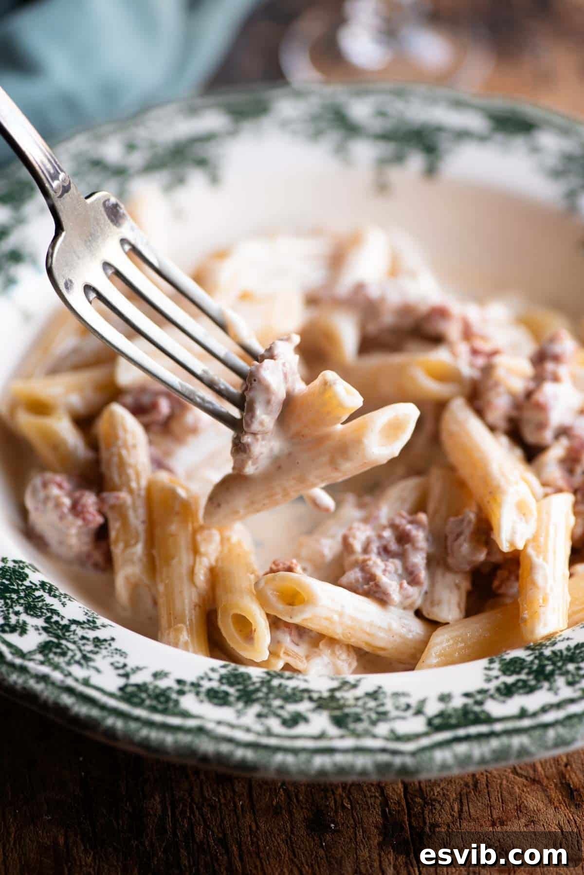 A close-up shot of a fork twirling a delectable bite of creamy sausage and truffle pasta, showcasing the rich sauce and perfectly cooked penne.