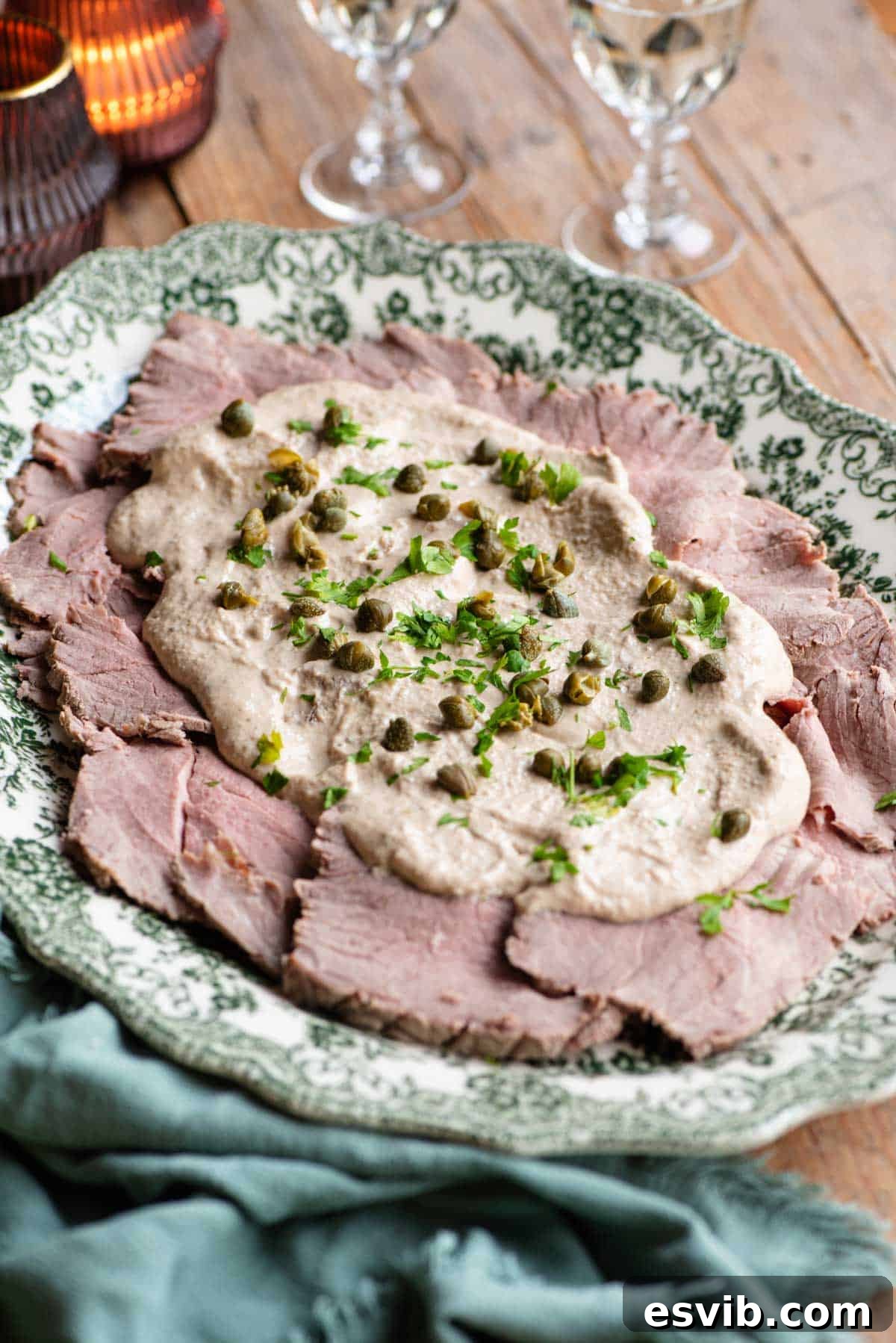 Beautifully presented Vitello Tonnato on a serving platter, adorned with a smooth tuna sauce, fresh capers, and a sprinkle of vibrant parsley.