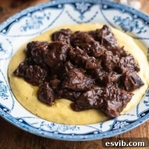 A close up cropped image of Carbonade beef stew on top of polenta.