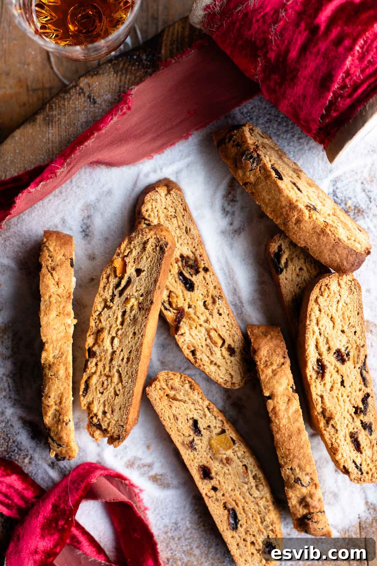 An overhead shot of panettone biscotti on a wooden surface with sugar and a red Christmas ribbon. Delicious, double-baked Italian cookies.