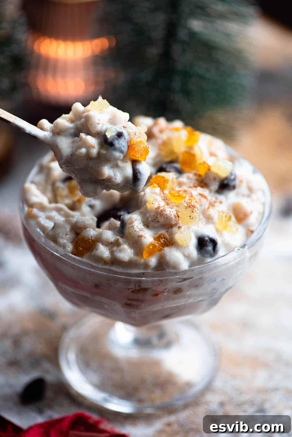 Cuccia The Sicilian Ricotta Delight 7 A close-up image of a spoon gracefully lifting a portion of creamy ricotta grain dessert from a small glass bowl, highlighting its rich texture and delicious appeal.