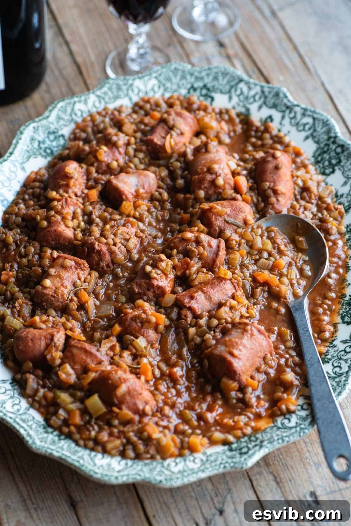 Italian sausages and lentils on a large serving plate sitting on a wooden table.