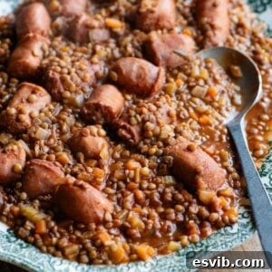 A cropped square image of Italian sausages and lentils on a serving plate.