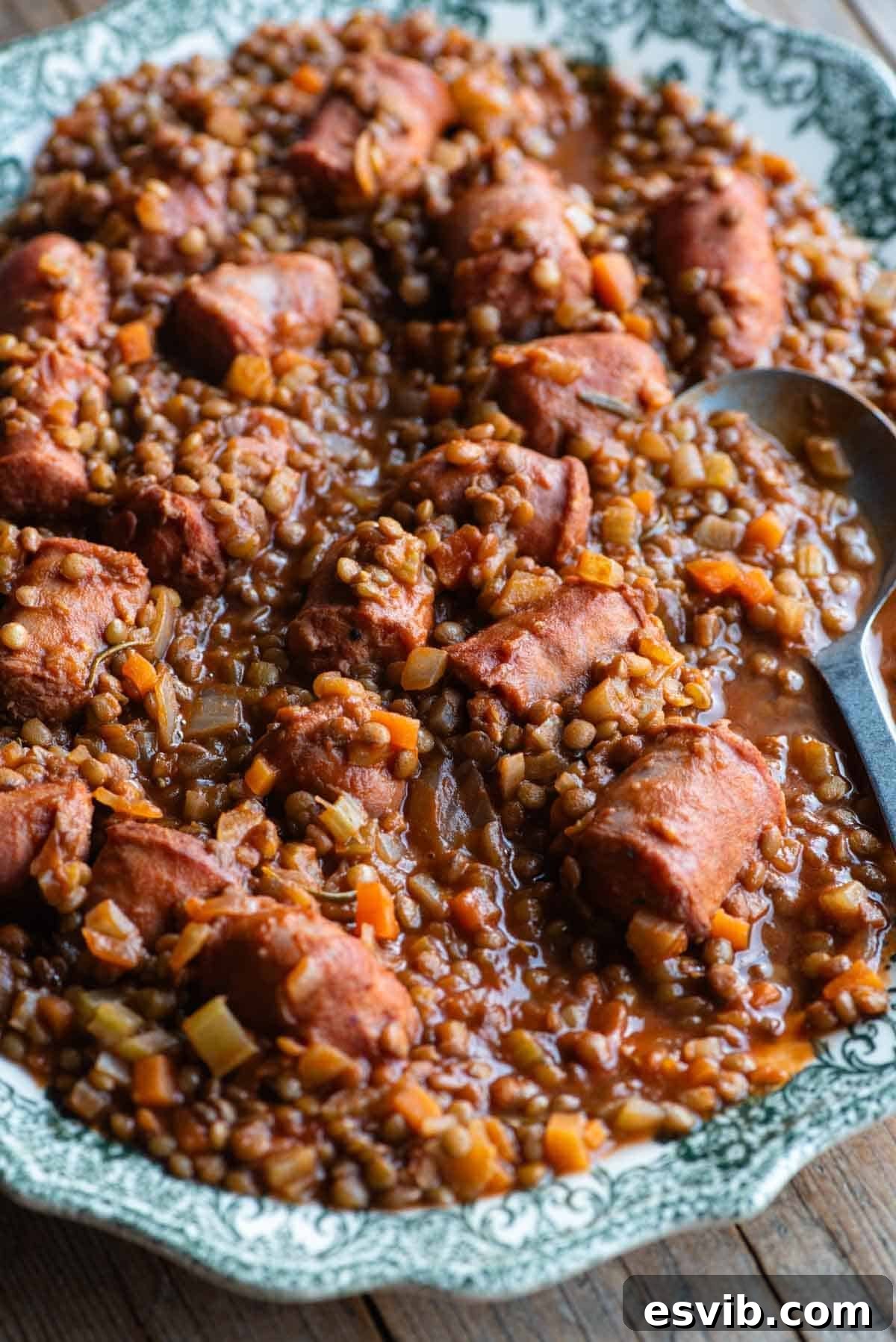 A close up of Italian sausages and lentils on a large plate with a serving spoon.