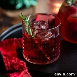 A close-up, cropped image of a vibrant red Italian Sbagliato Rosso cocktail in a short glass, elegantly garnished with a fresh rosemary sprig.