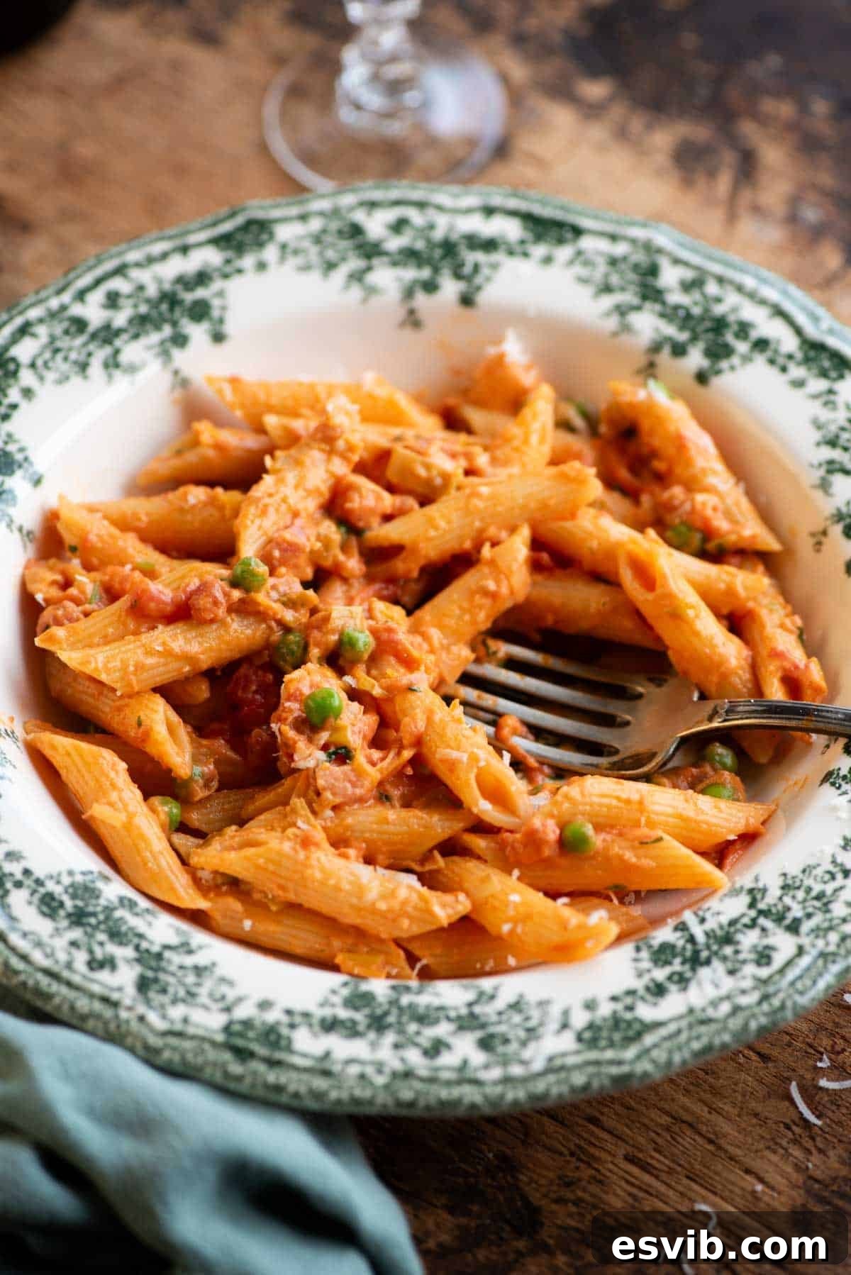 A close up of a creamy Tuscan pasta in a bowl called 'pasta alle 7 P' the bowl is on a wooden table.