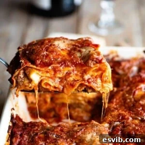 A cropped close up image of a slice of Neapolitan lasagna, showing its vibrant layers and rich sauce.