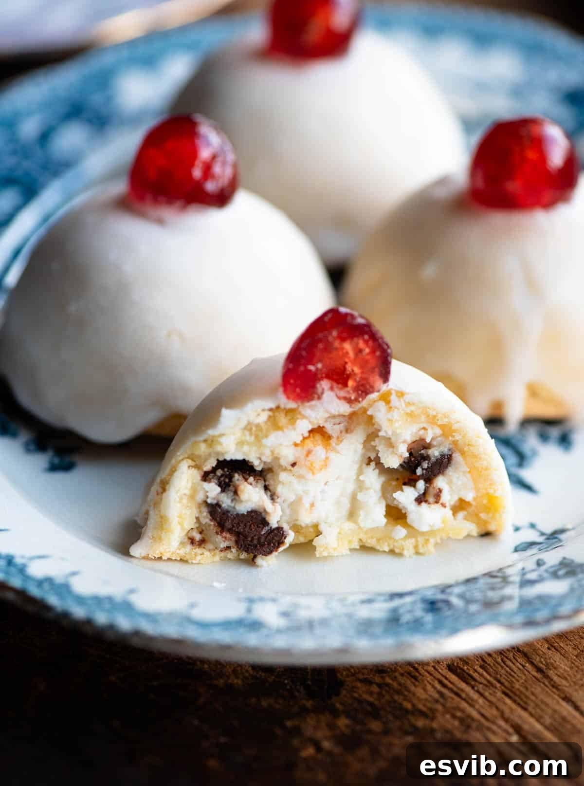 A close-up view of a Minne di Sant'Agata pastry, beautifully cut in half, revealing its rich and creamy ricotta filling with visible chocolate chips and colorful candied fruit.