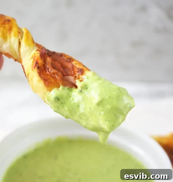 Close-up of Sour Cream Pesto Dip in a bowl, surrounded by golden Prosciutto Dippers.