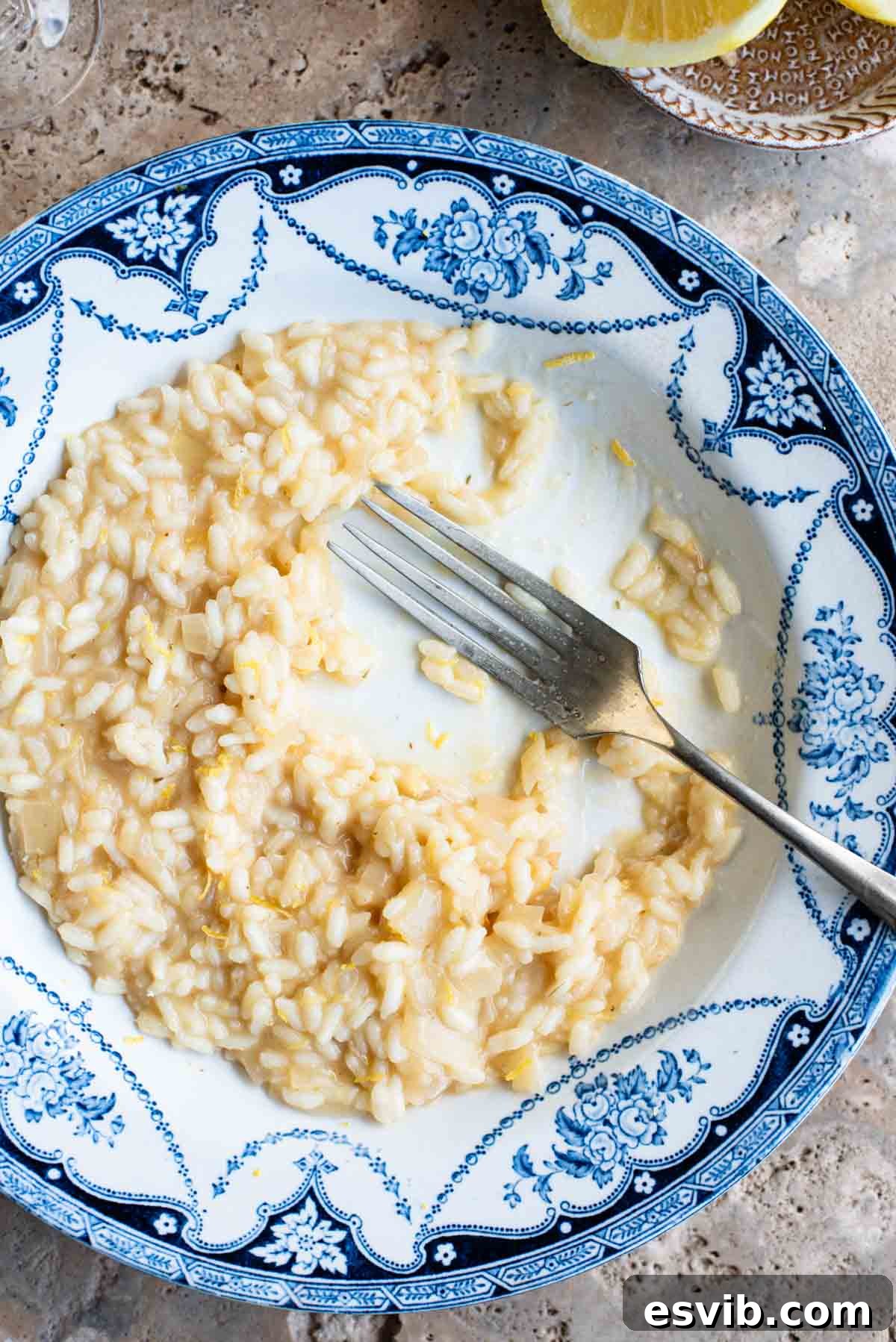 Zesty Lemon Risotto 6 An overhead close-up shot of a partially eaten bowl of creamy lemon risotto, with a fork resting in the bowl, highlighting its rich texture and inviting presentation.