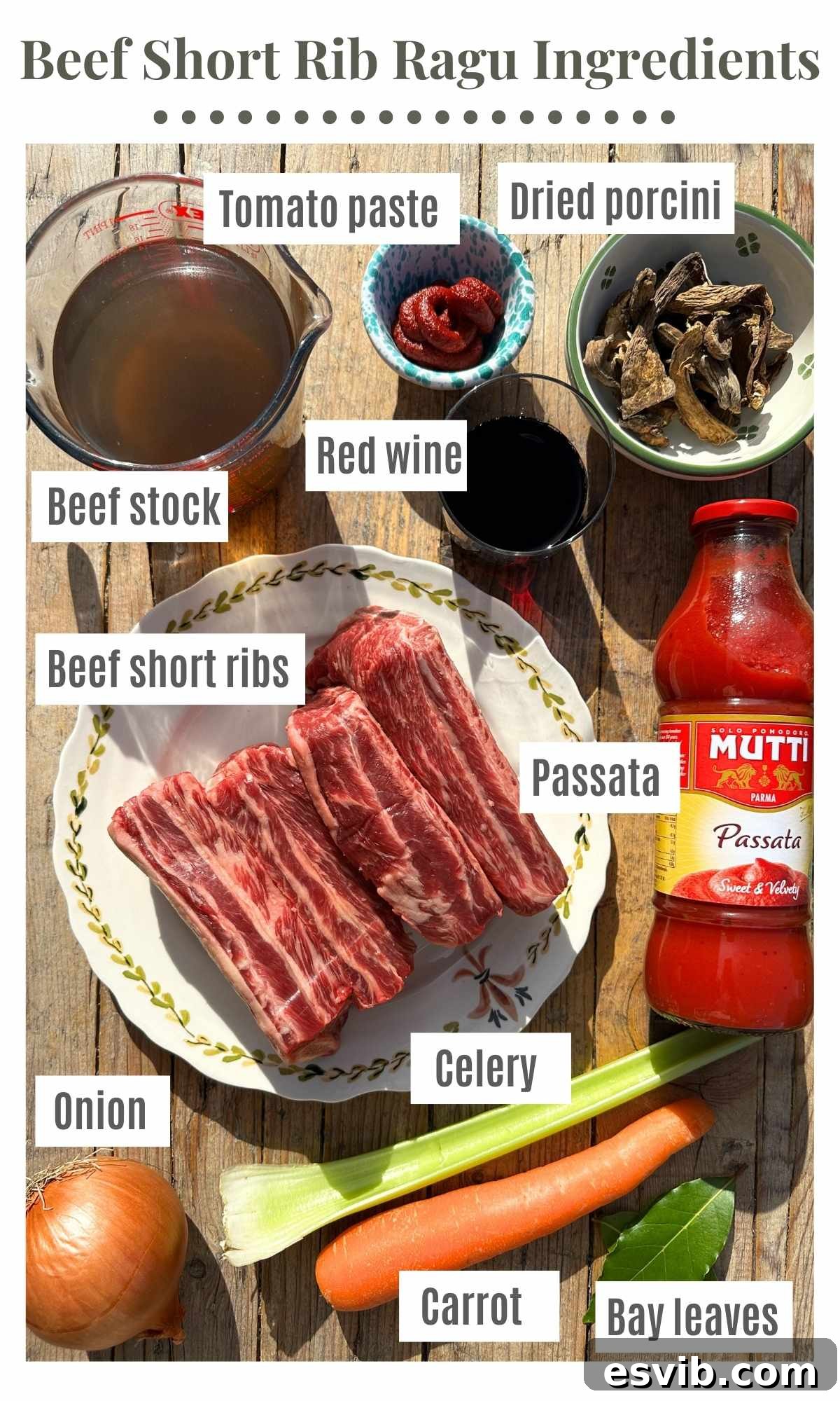 Beef short rib ragu ingredients neatly arranged on a rustic wooden surface, clearly showing raw beef short ribs, diced onion, celery, carrot, beef stock, concentrated tomato paste, a bottle of red wine, dried porcini mushrooms, smooth passata, and aromatic bay leaves, all prepared for cooking.