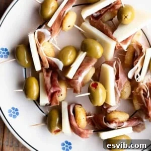 A close up of fried gnocchi on skewers with prosciutto, pecorino and olives.