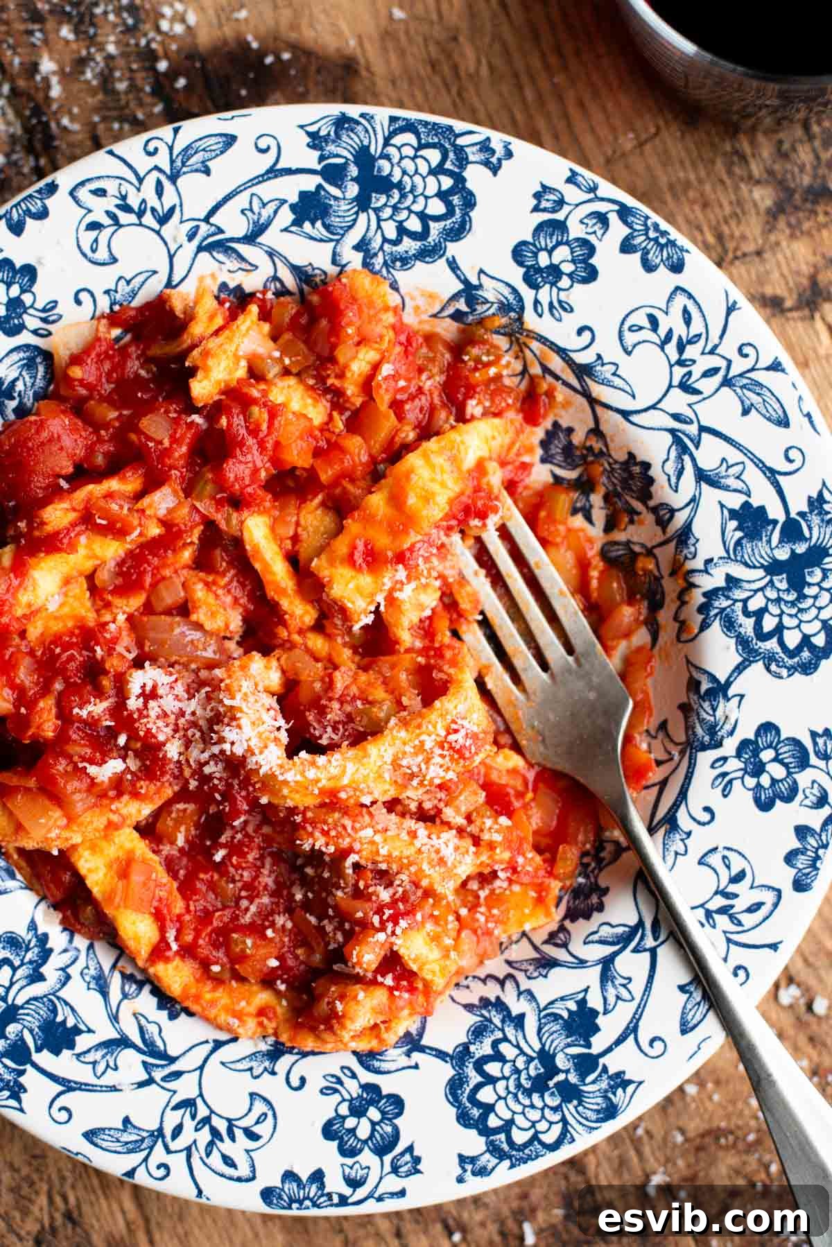 A close up of a fork in a bowl of Italian Trippa Finta (omelette in tomato sauce).