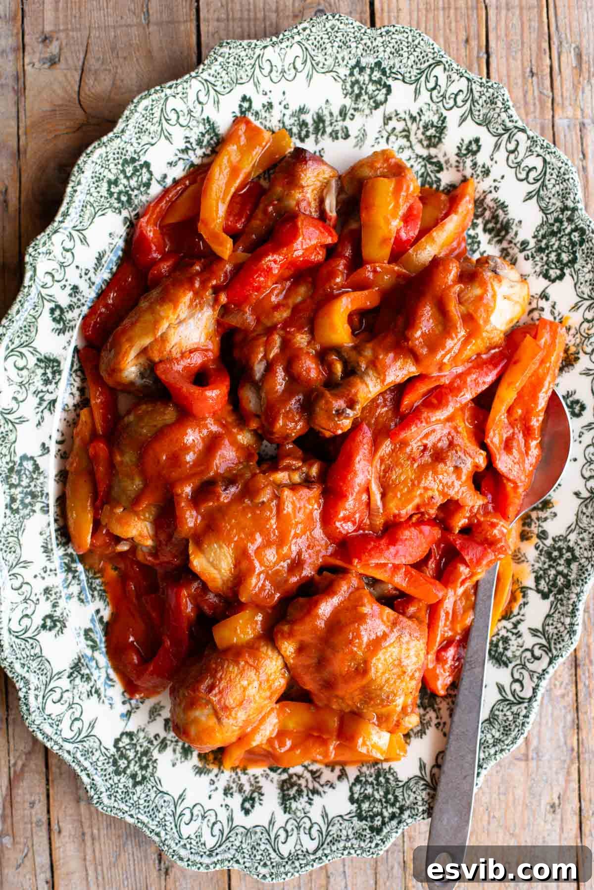 Italian chicken and peppers in a tomato sauce on a large platter serving plate on a rustic wooden surface.