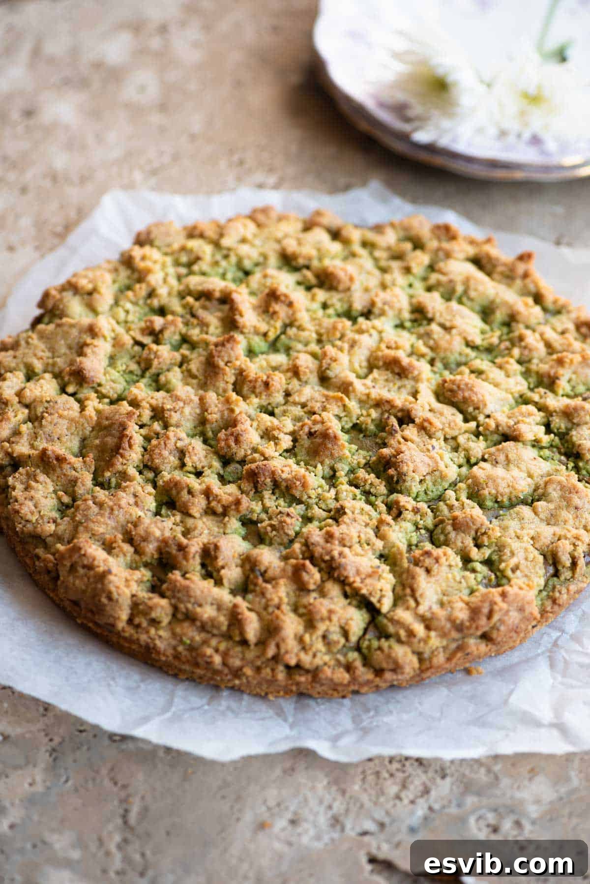 An Italian pistachio crumb cake sitting on a travertine surface.