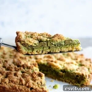A close cup of a slice of pistachio crumb cake being help up on a cake server.