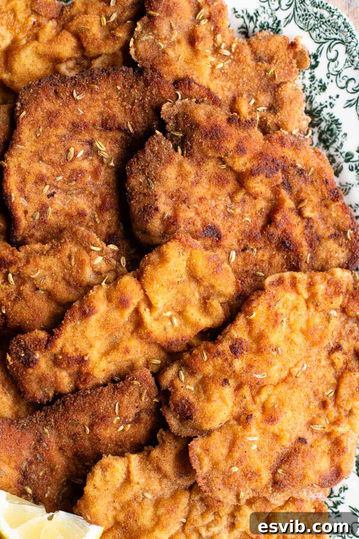 A close up of breaded pork fillet with fennel seeds on a plate.