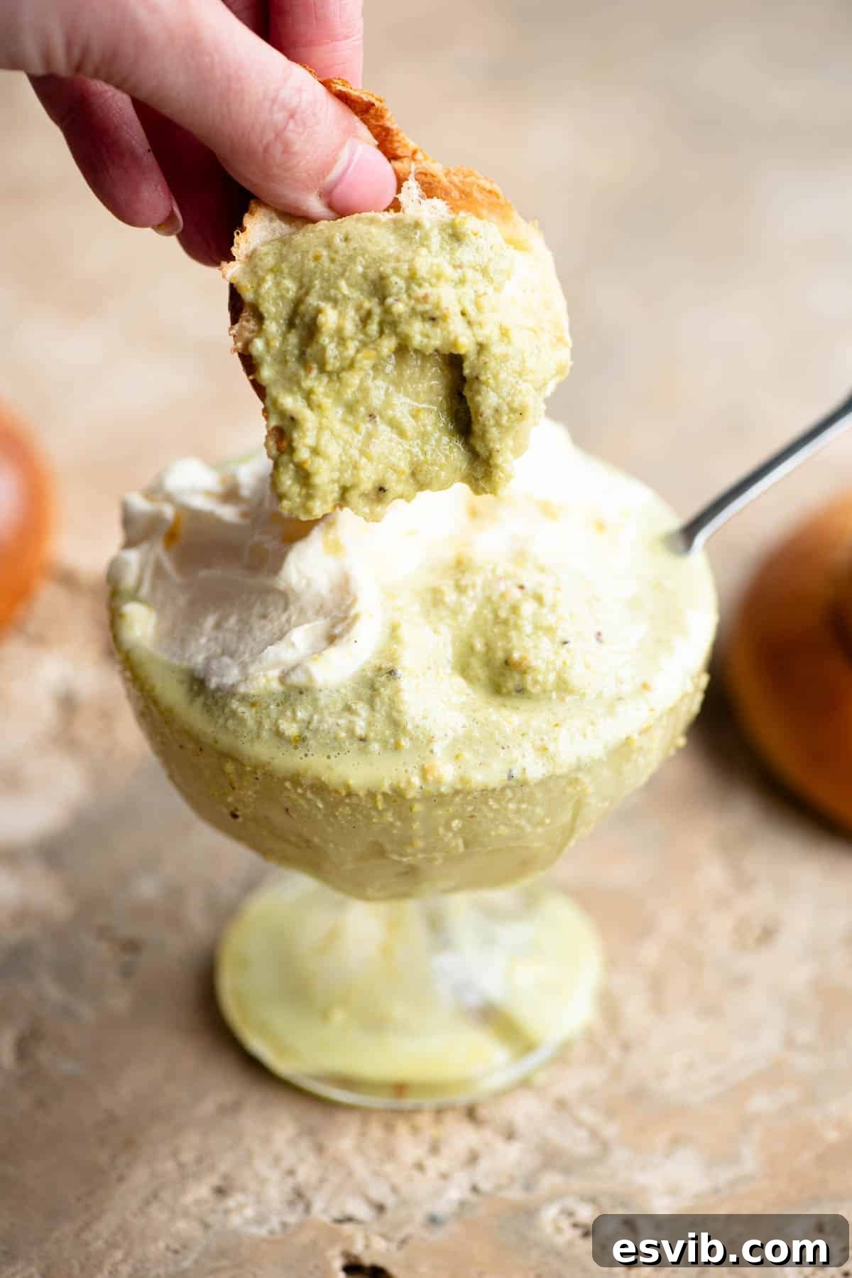 A piece of brioche being dunked into pistachio granita.