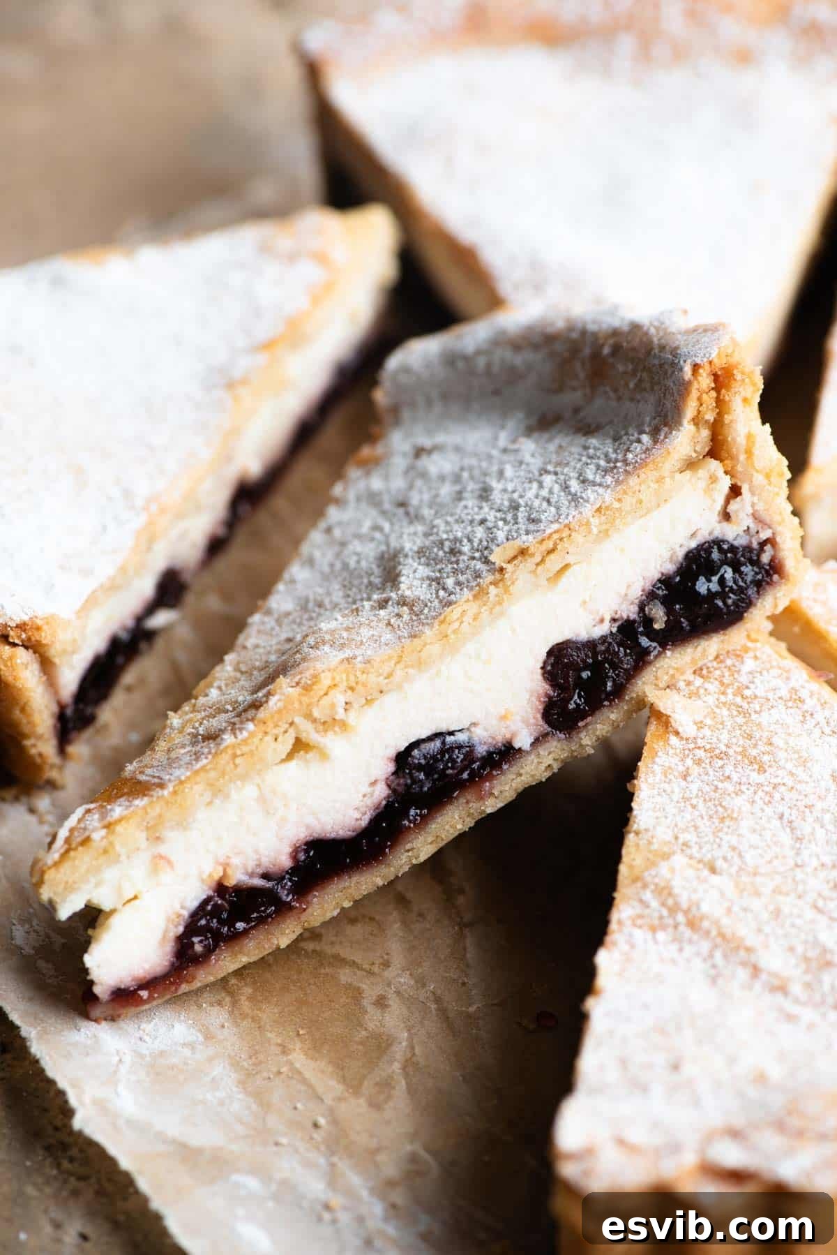 Ruby Cherry Ricotta Crostata 2 A close up of a slice of Crostata Ricotta e Visciole (ricotta and cherry tart) dusted with powdered sugar, showcasing its creamy filling and golden crust.
