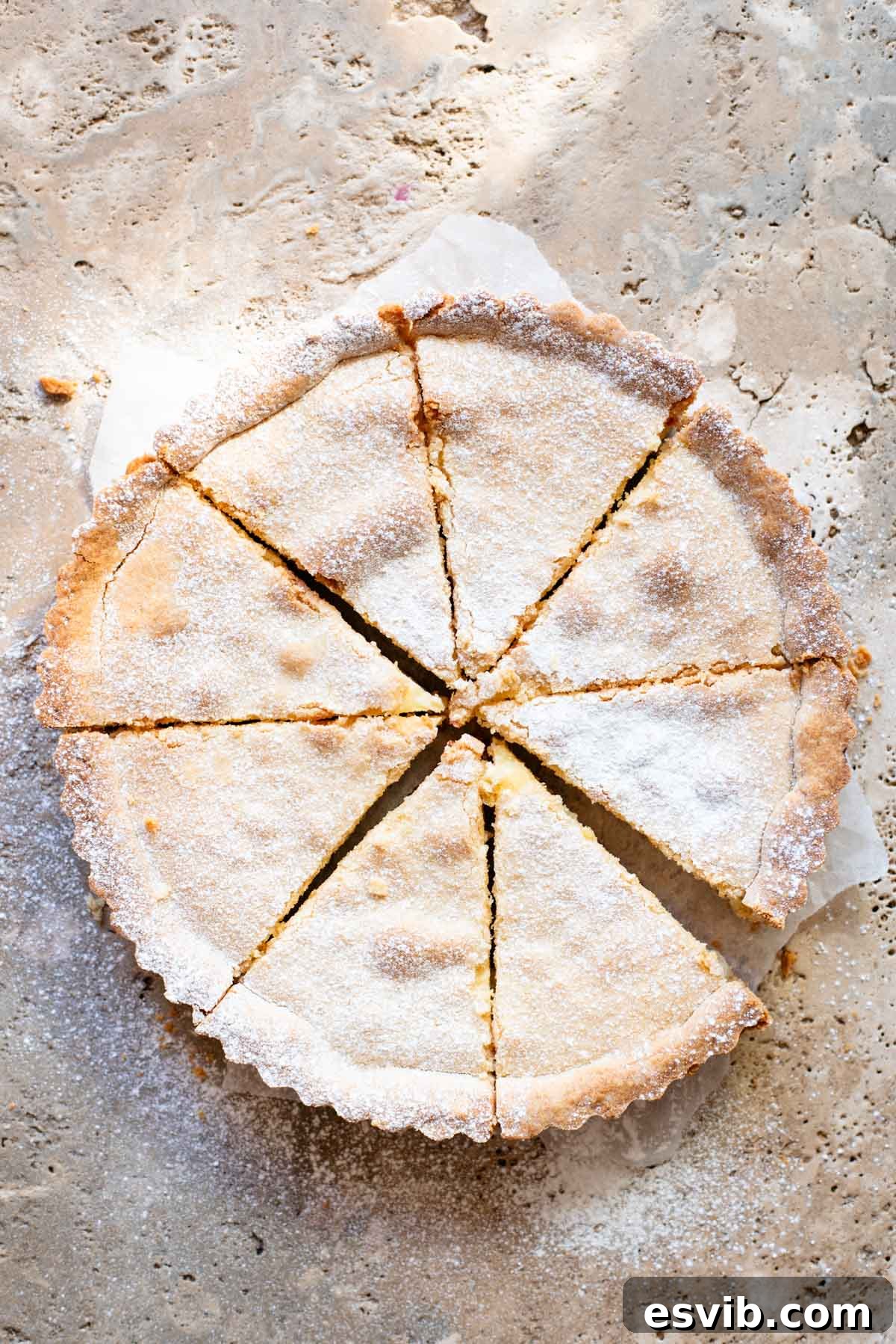 Ruby Cherry Ricotta Crostata 7 A beautifully baked Crostata Ricotta e Visciole, cut into 8 perfect slices and generously dusted with powdered sugar, sitting elegantly on a travertine surface.