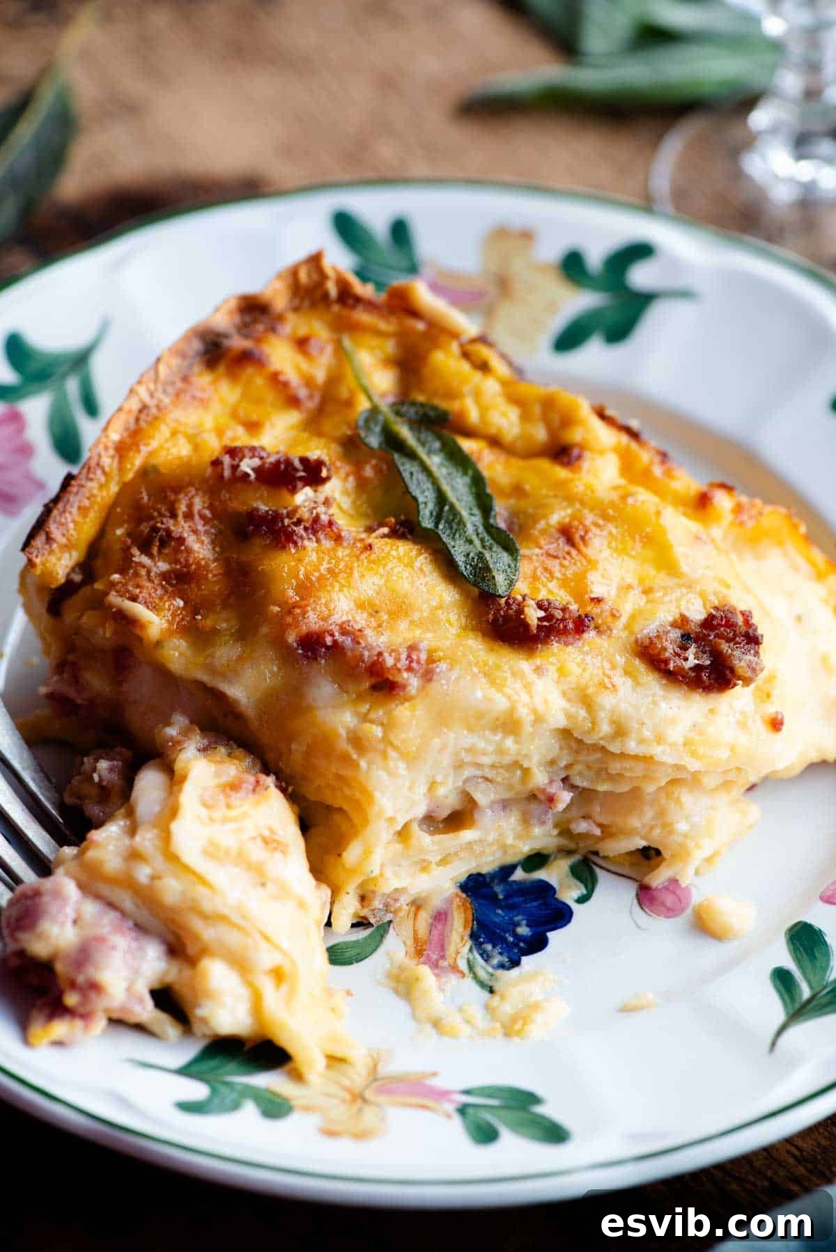 A perfectly portioned slice of butternut squash lasagna, showcasing its beautiful layers of pasta, creamy sauce, and sausage, served on a charming floral patterned plate.