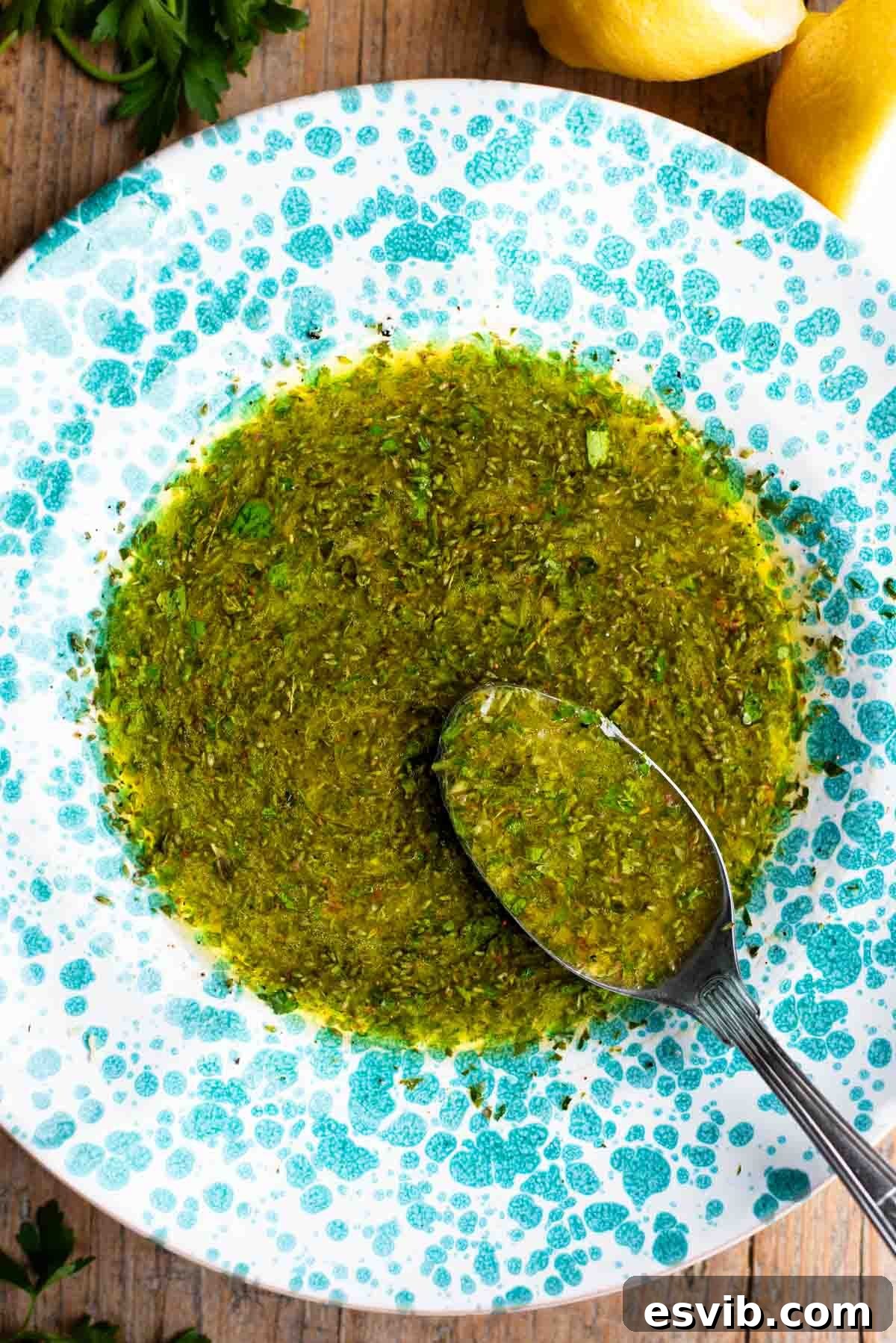 Salmoriglio: Zesty Southern Italian Herb Sauce 5 Salmoriglio sauce in a vibrant green splatter pattern bowl with a spoon, ready to serve.