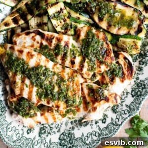 A close up of grilled chicken and veg on a plate topped with Salmoriglio herb sauce.
