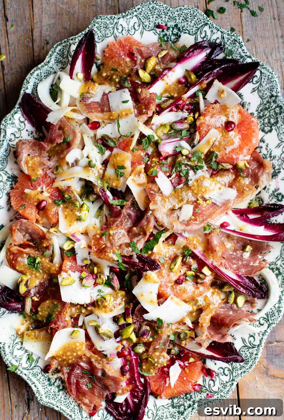 A green serving platter with a festive, colourful salad filled with blood orange, radicchio, fennel, pomegranate, pistachios and prosciutto.
