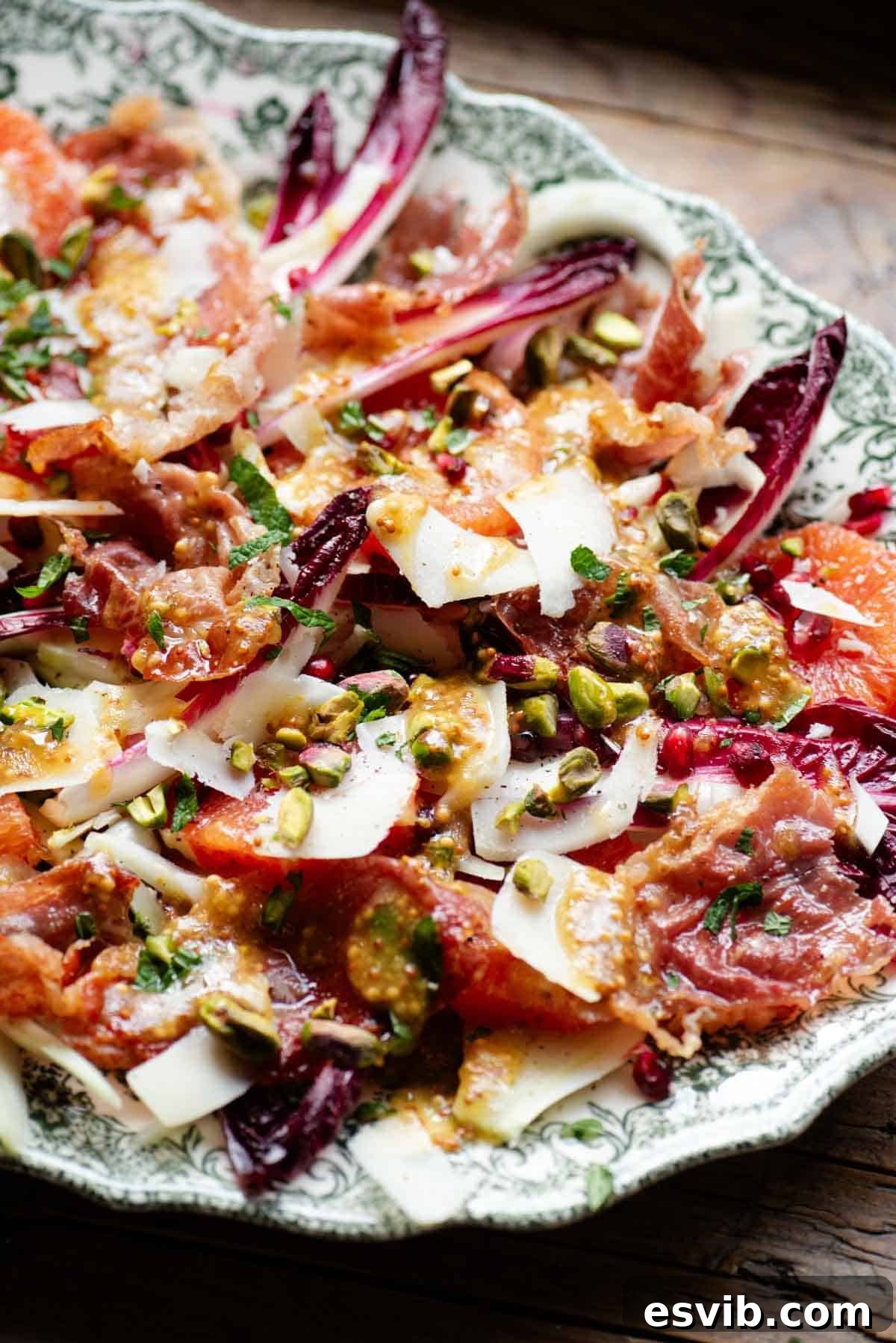 A side shot of a festive salad with blood orange, radicchio, prosciutto, pecorino, pomegranate and pistachios.