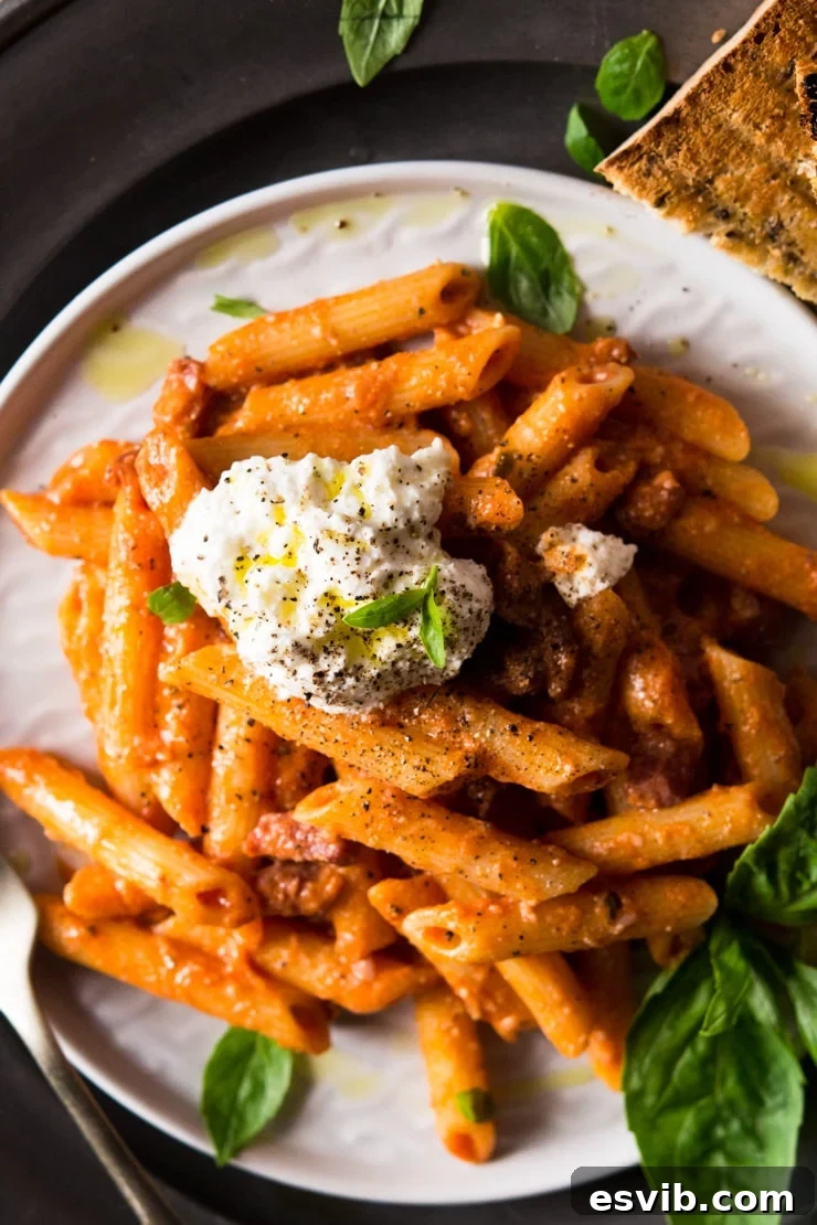 A close up of penne pasta with pancetta, topped with a generous dollop of creamy ricotta cheese and fresh black pepper