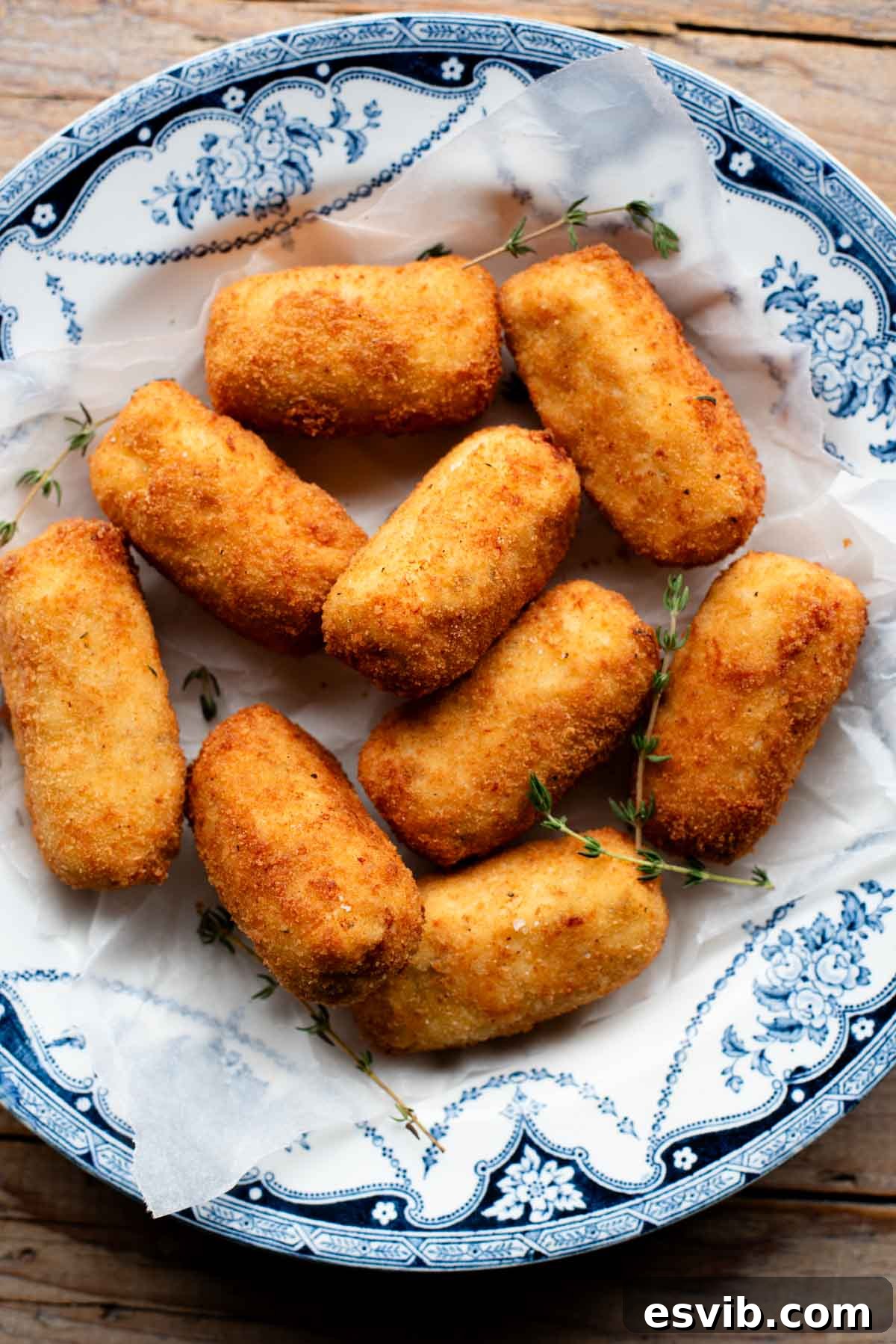 Creamy Chicken Ricotta Bites 2 An overhead shot of golden-brown chicken croquettes in a rustic blue bowl, garnished with fresh sprigs of thyme, ready to be served.